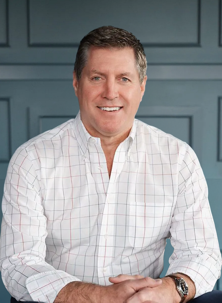 Smiling man in checked shirt with blue wall background.