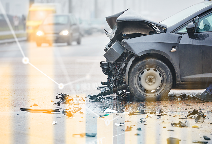 Crashed car with a damaged front end on the road, debris scattered on the pavement under cloudy weather conditions.