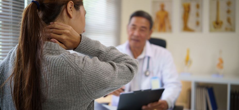 Woman with neck pain consulting a doctor in a medical office, seeking advice and treatment options.