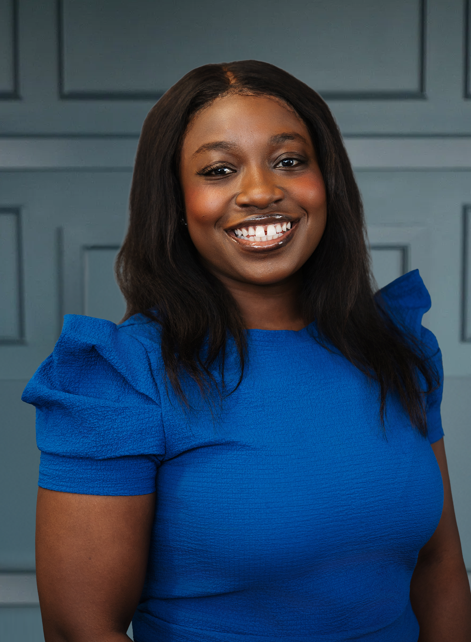 Smiling woman in blue dress against a paneled blue background.