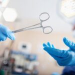 Surgeons in blue scrubs and gloves pass surgical scissors in an operating room.