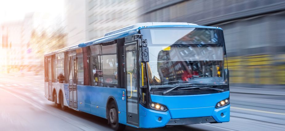 Blue city bus driving on street with motion blur in an urban setting.