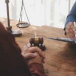 Two individuals discussing legal matters at a table with a gavel and scales of justice.