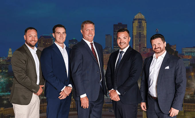 Five professional men in suits posing in front of a city skyline at night.